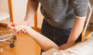 Fizjoterapeuta bada rękę pacjentki, oceniając bliznę po operacji cieśni nadgarstka.
