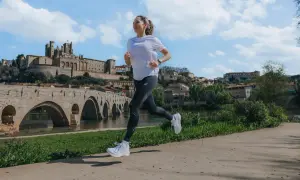 Kobieta biegnie nad rzeką, mijając zabytkowy most i miasto. Nawet przy lekkiej kolce podczas biegania, widok jest piękny.