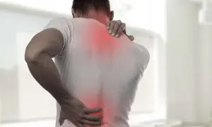 Mężczyzna z bólem pleców i karku, któremu pomaga maść rozgrzewająca.