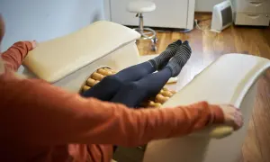Kobieta w skarpetkach w paski relaksuje nogi na urządzeniu rolletic, które masuje jej łydki.