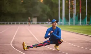 Kobieta rozciąga się na bieżni, przygotowując mięśnie do biegania.