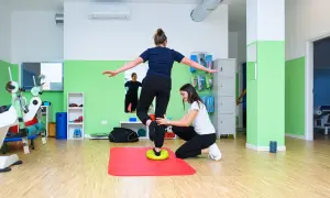 Fizjoterapeutka pomaga pacjentce ćwiczyć równowagę, rozwijając propriocepcję na poduszce balansującej.