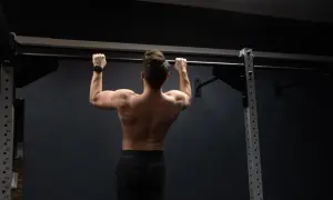 Mężczyzna wykonuje ćwiczenie pull up na drążku, budując siłę pleców i ramion.