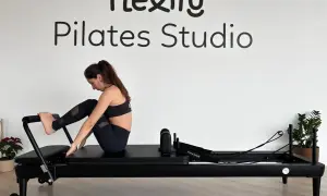 Kobieta ćwiczy na reformerze. Widoczne napisy "Flexity Pilates Studio". To dowód na pilates efekty po miesiącu.