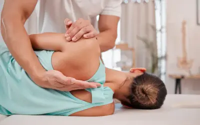 Fizjoterapeuta pomaga pacjentce zmagającej się z neurologiczne bóle mięśni, wykonując delikatny masaż barku.
