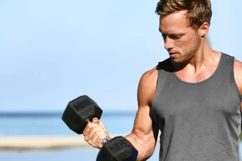 Mężczyzna ćwiczy biceps z hantlem, zastanawiając się, ile serii na biceps w tygodniu da najlepsze efekty.