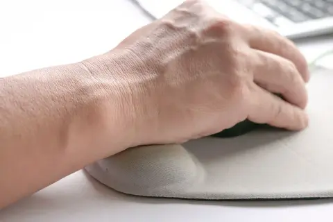 Dłoń opiera się na podkładce pod mysz, łagodząc ból nadgarstka.