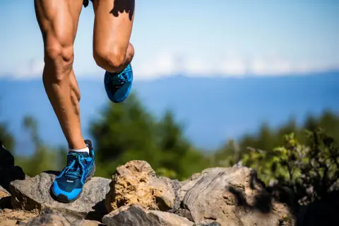 Nogi biegacza w niebieskich butach na kamienistym szlaku. Czy to już 100 km ultramaratonu?
