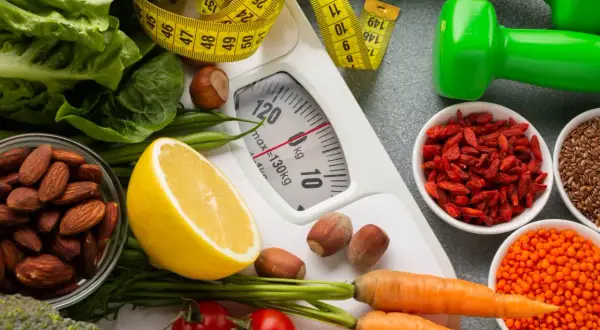Zdrowa dieta i ćwiczenia to klucz do dobrego samopoczucia. Waga, miarka, warzywa, owoce i orzechy symbolizują drogę do zdrowia.