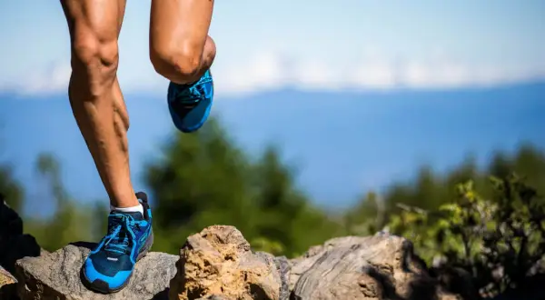 Nogi biegacza w niebieskich butach na kamienistym szlaku. Czy to już 100 km ultramaratonu?