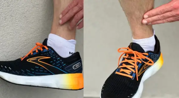 Biegacz dotyka łydki, być może z powodu bólu shin splints. Na stopach ma czarne buty biegowe Brooks z pomarańczowymi sznurówkami.