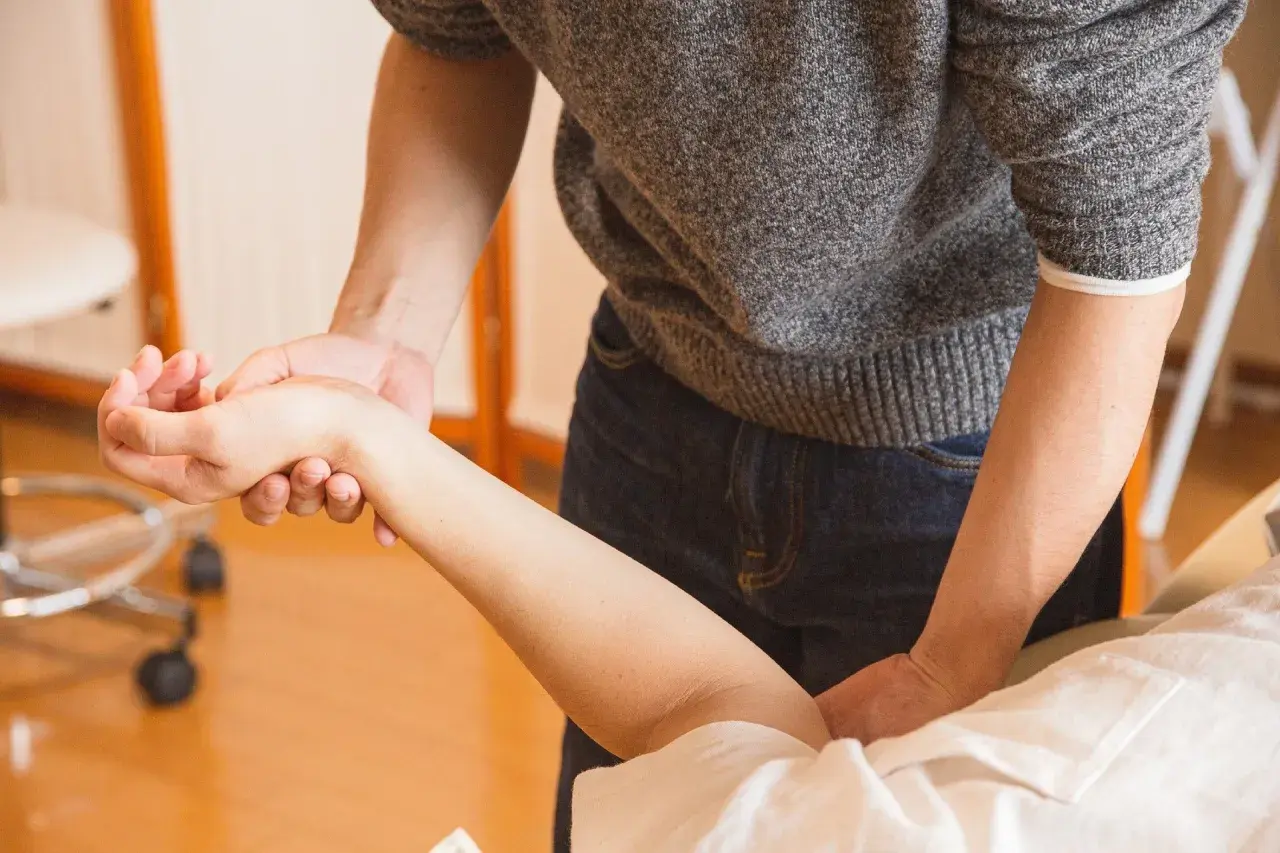 Fizjoterapeuta bada rękę pacjentki, oceniając bliznę po operacji cieśni nadgarstka.