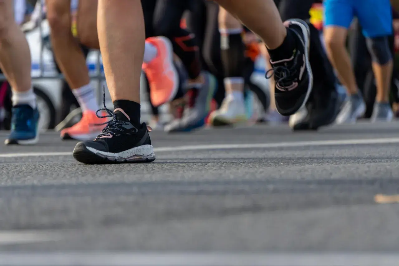 Nogi biegaczy w butach sportowych na trasie. To właśnie jest jogging, czyli bieganie dla zdrowia i przyjemności.