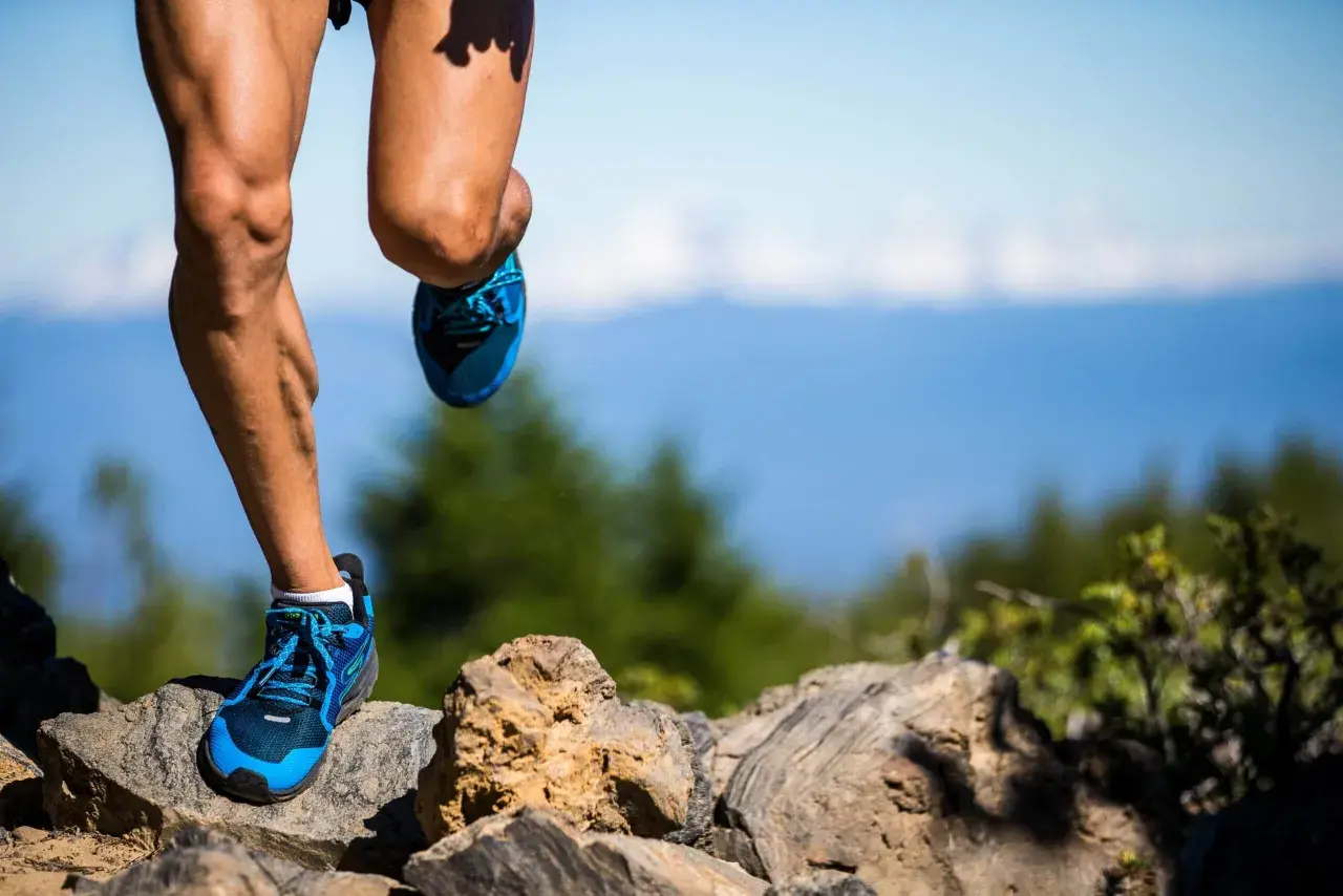 Nogi biegacza w niebieskich butach na kamienistym szlaku. Czy to już 100 km ultramaratonu?