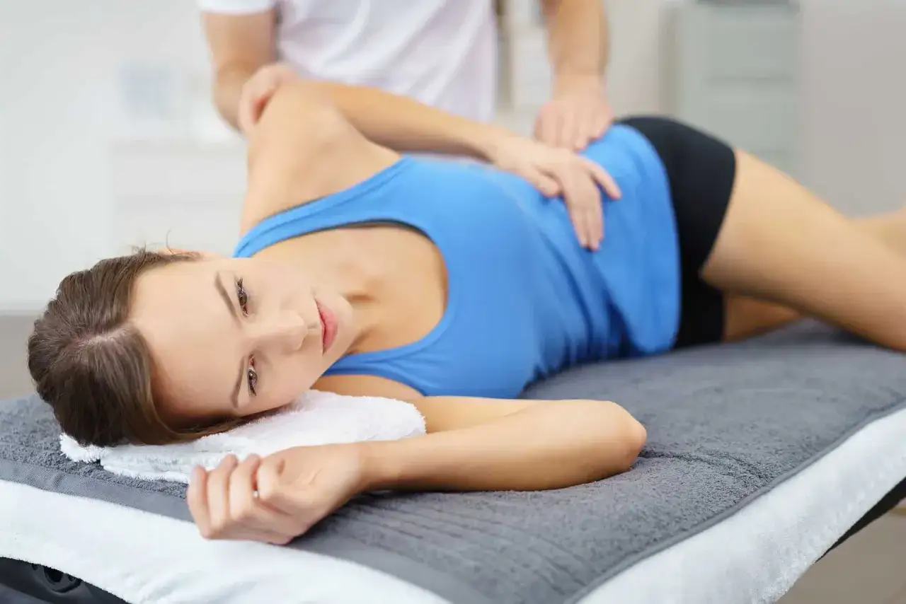 Fizjoterapeuta masuje biodro pacjentki, pomagając jej w leczeniu zapalenia kaletki biodrowej.