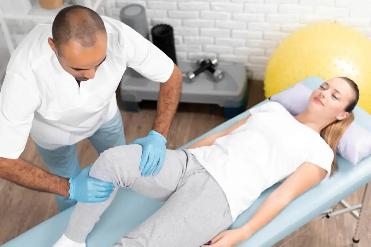 Fizjoterapeuta bada kolano pacjentki po urazie, być może zerwaniu acl.