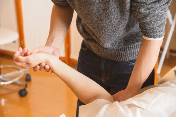 Fizjoterapeuta bada rękę pacjentki, oceniając bliznę po operacji cieśni nadgarstka.