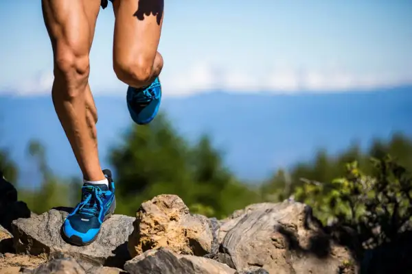 Nogi biegacza w niebieskich butach na kamienistym szlaku. Czy to już 100 km ultramaratonu?